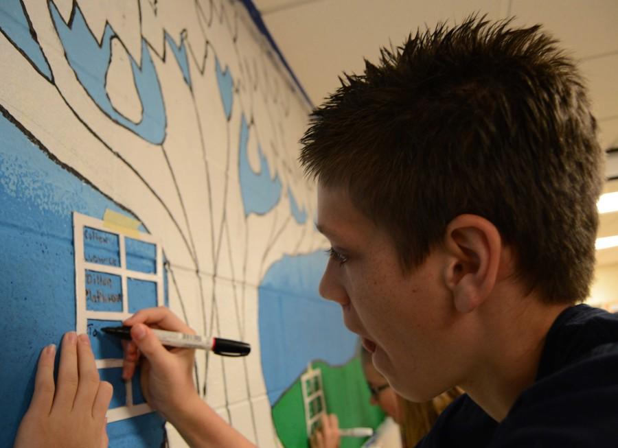 Tom Constertina adds his name to the class mural. “I really liked the speaker,” he said. “He offered a lot of philosphical ideas.”
