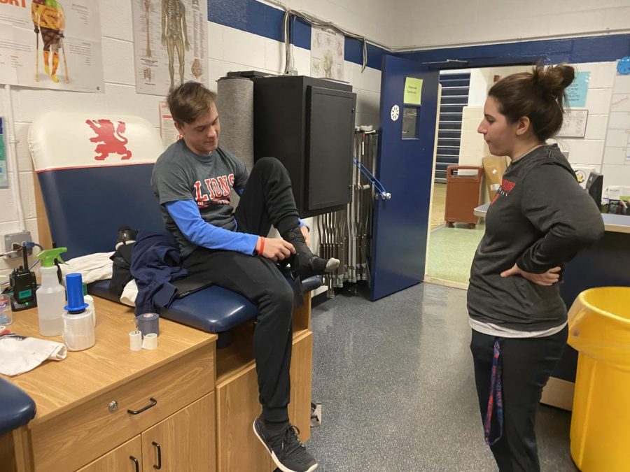 Freshman Tyler Bielfeldt works in the athletic training room with Coach Gina Garro.