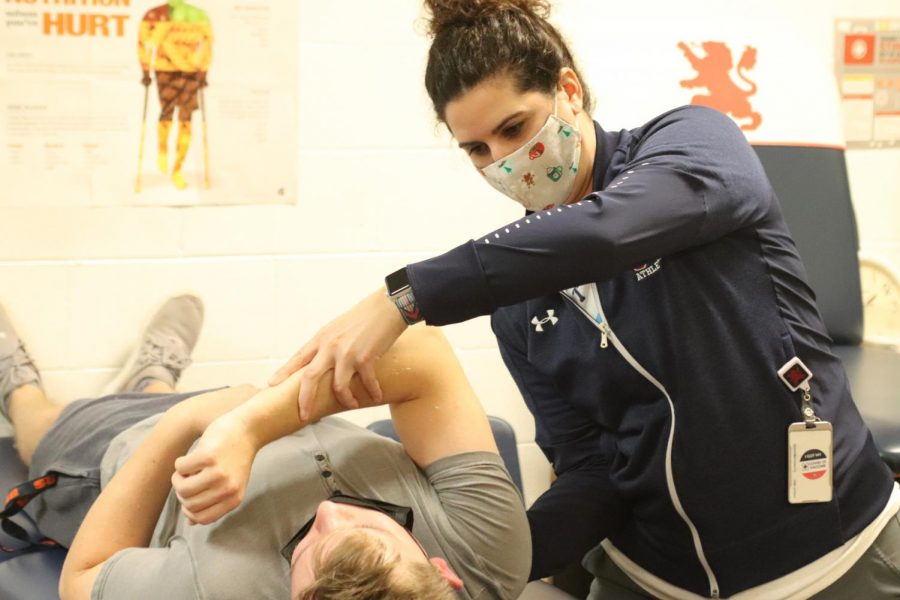 Ms. Garro assists a student athlete with his injury.	        Photo by Mary Stauder